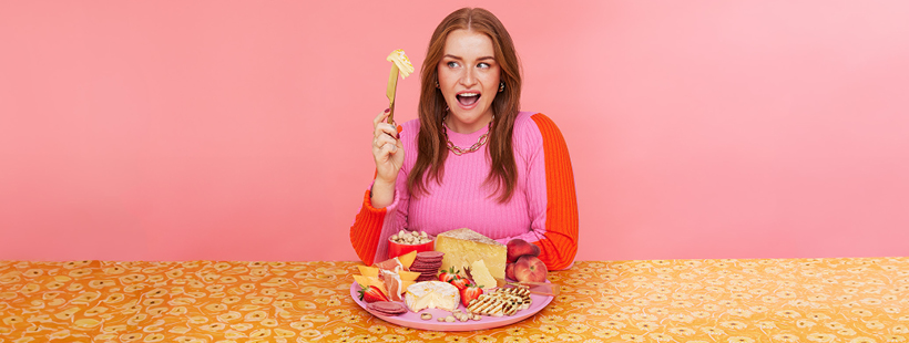 Jasmin Watson is looking excitedly at a piece of cheese held up on a knife.