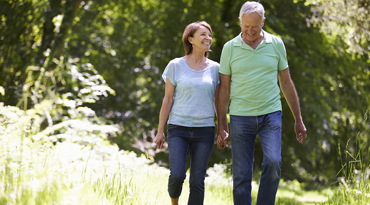 An older couple holds hands while walking outdoors