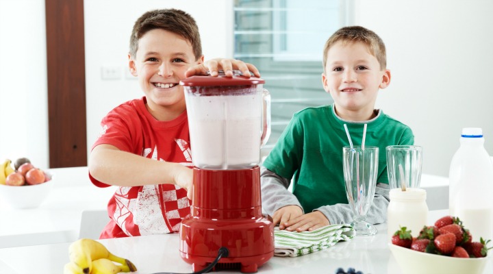 Two boys make healthy smoothies in the kitchen