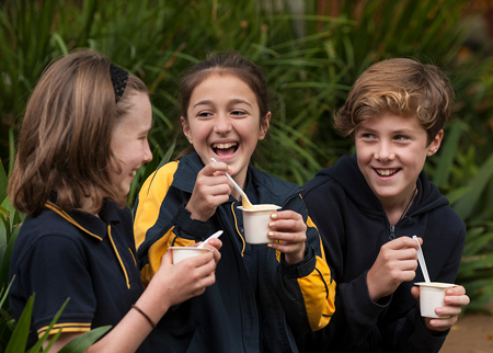School kids eating tubs of yoghurt