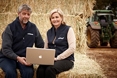 Two dairy farmers using a laptop on their farm