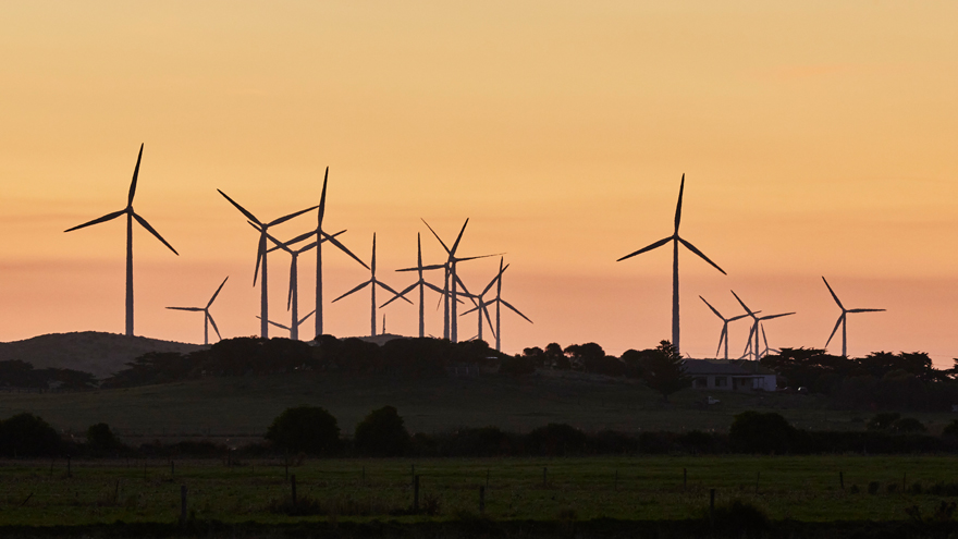 Landscape shot of wind turbines, sunset in distance